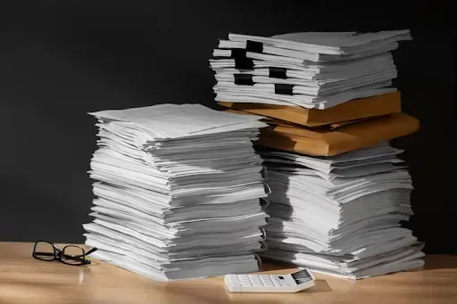 Stacks of paperwork and folders on a desk, ready for legal document shredding.