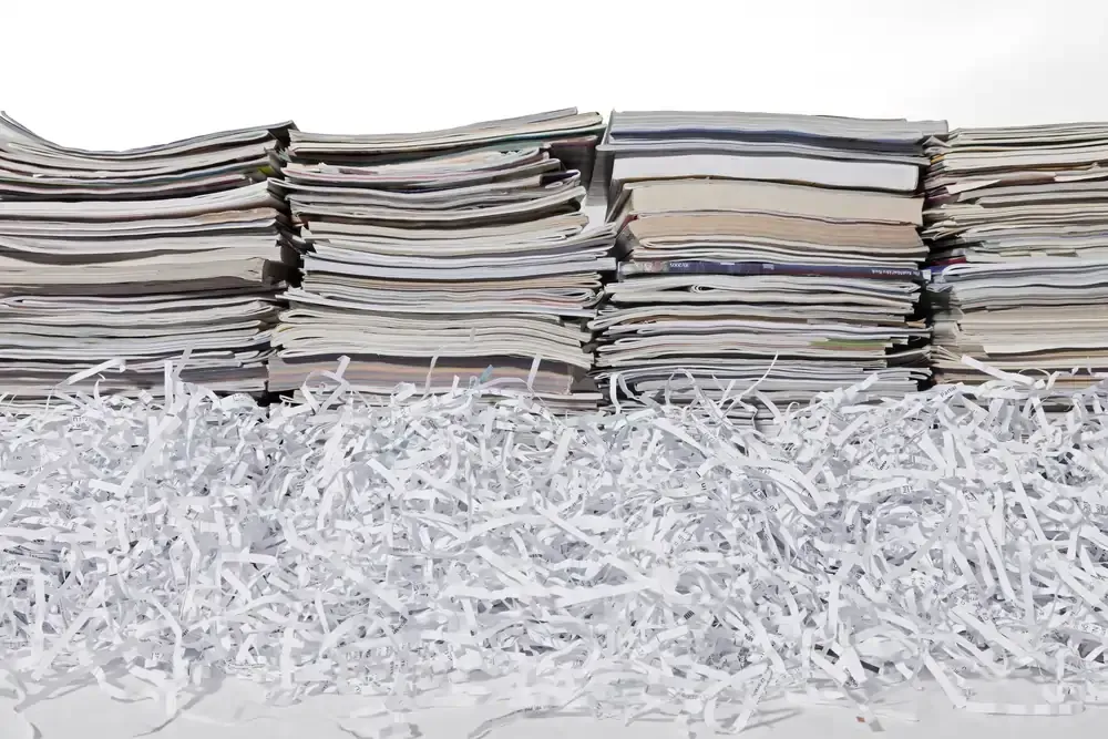 Stacks of magazines next to shredded paper, showing secure disposal by the best shredding company in California.