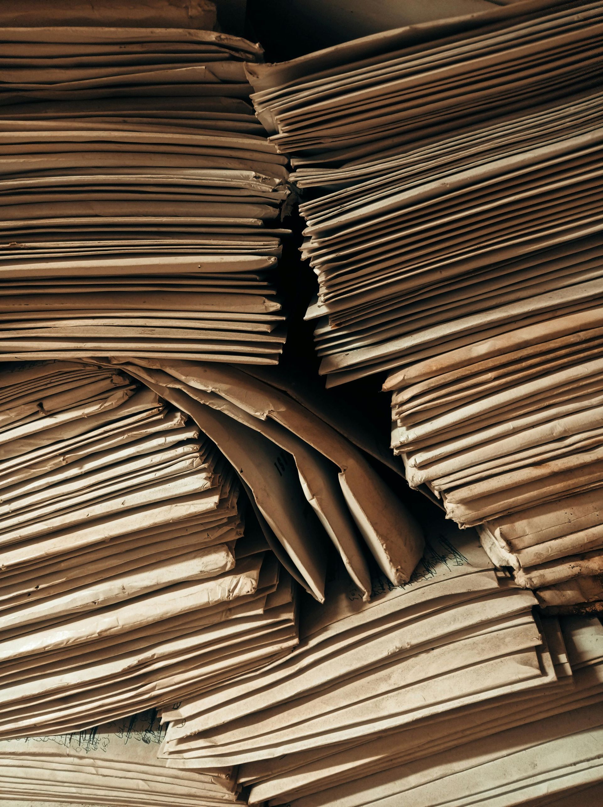 Stacks of folded, vintage brown paper or documents viewed from above, with edges showing layered textures.