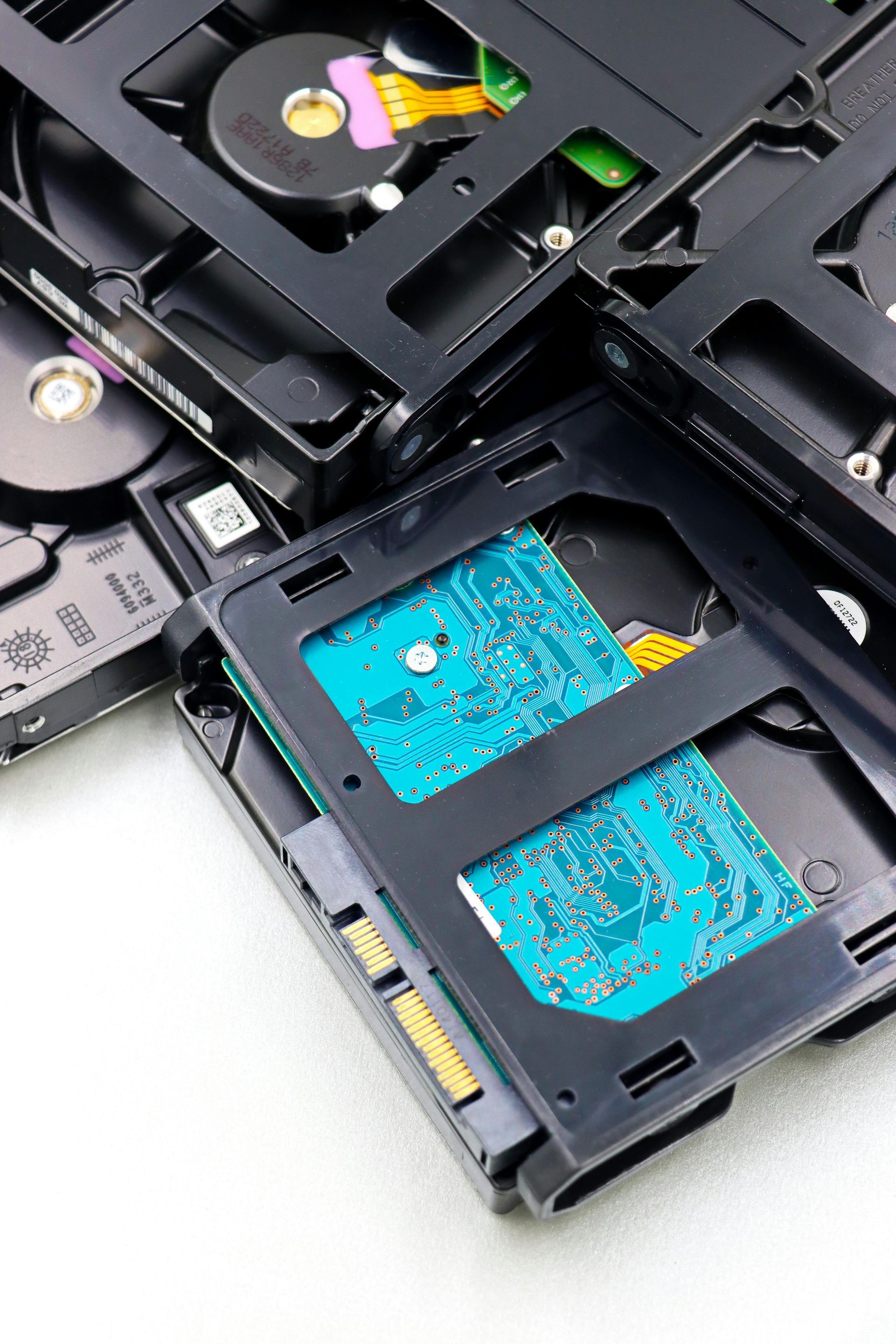 Several hard disk drives stacked together, with one positioned in the foreground showing its blue circuit board.