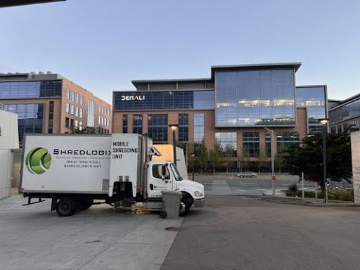 Shredlogix mobile truck parked outside a corporate building providing scheduled shredding service for secure document disposal.