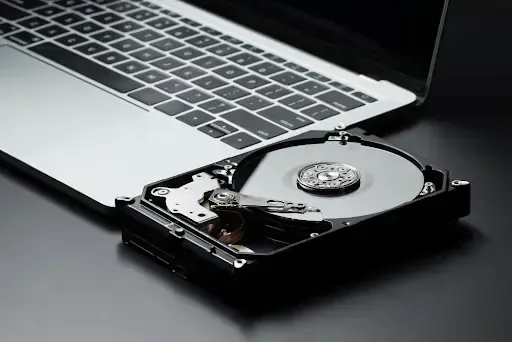 Hard drive vs paper shredding concept with laptop and open hard drive.