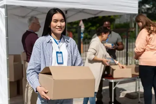 Volunteers at a community event holding boxes, promoting mobile paper shredding San Jose.
