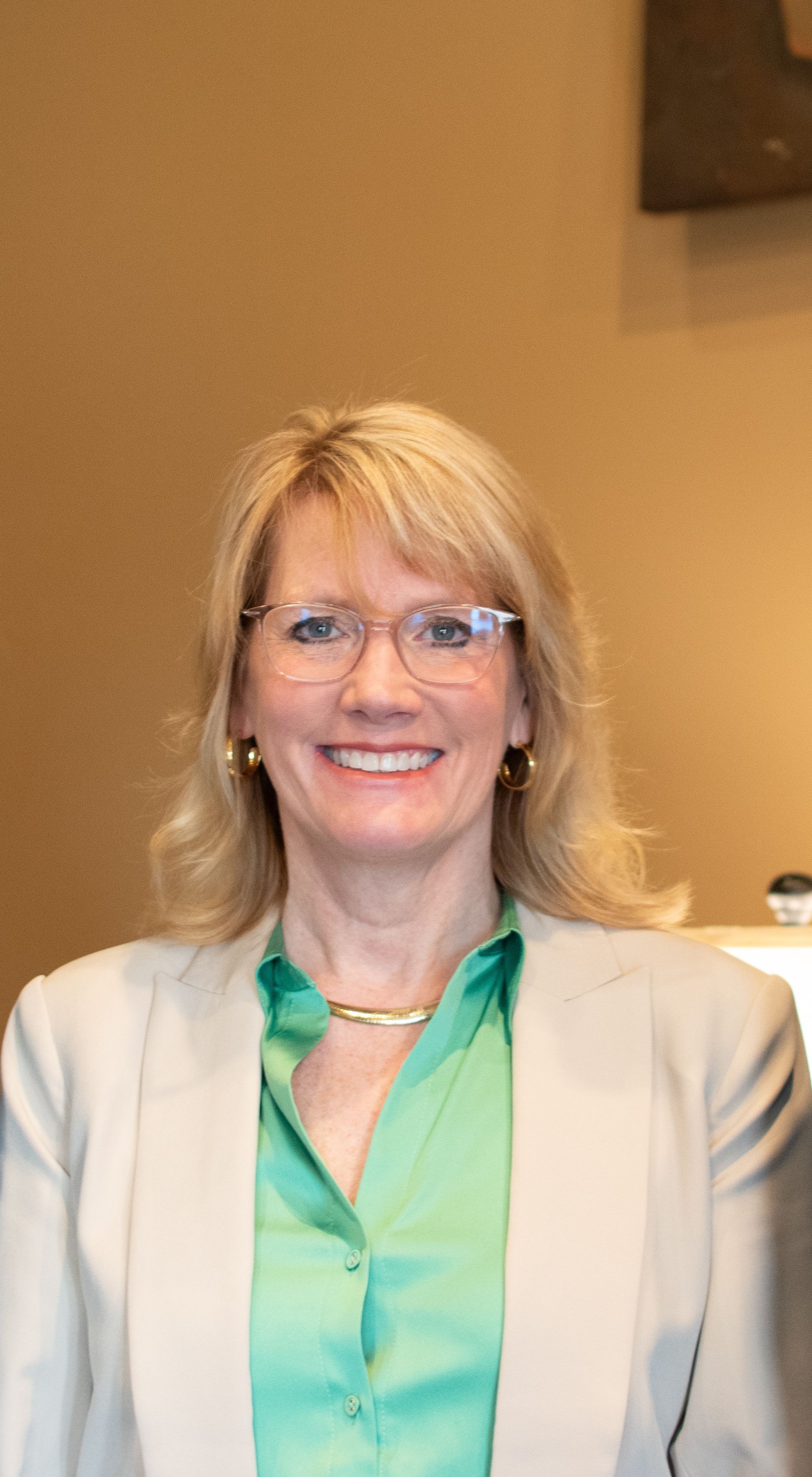 A woman wearing glasses and a green shirt is smiling for the camera.
