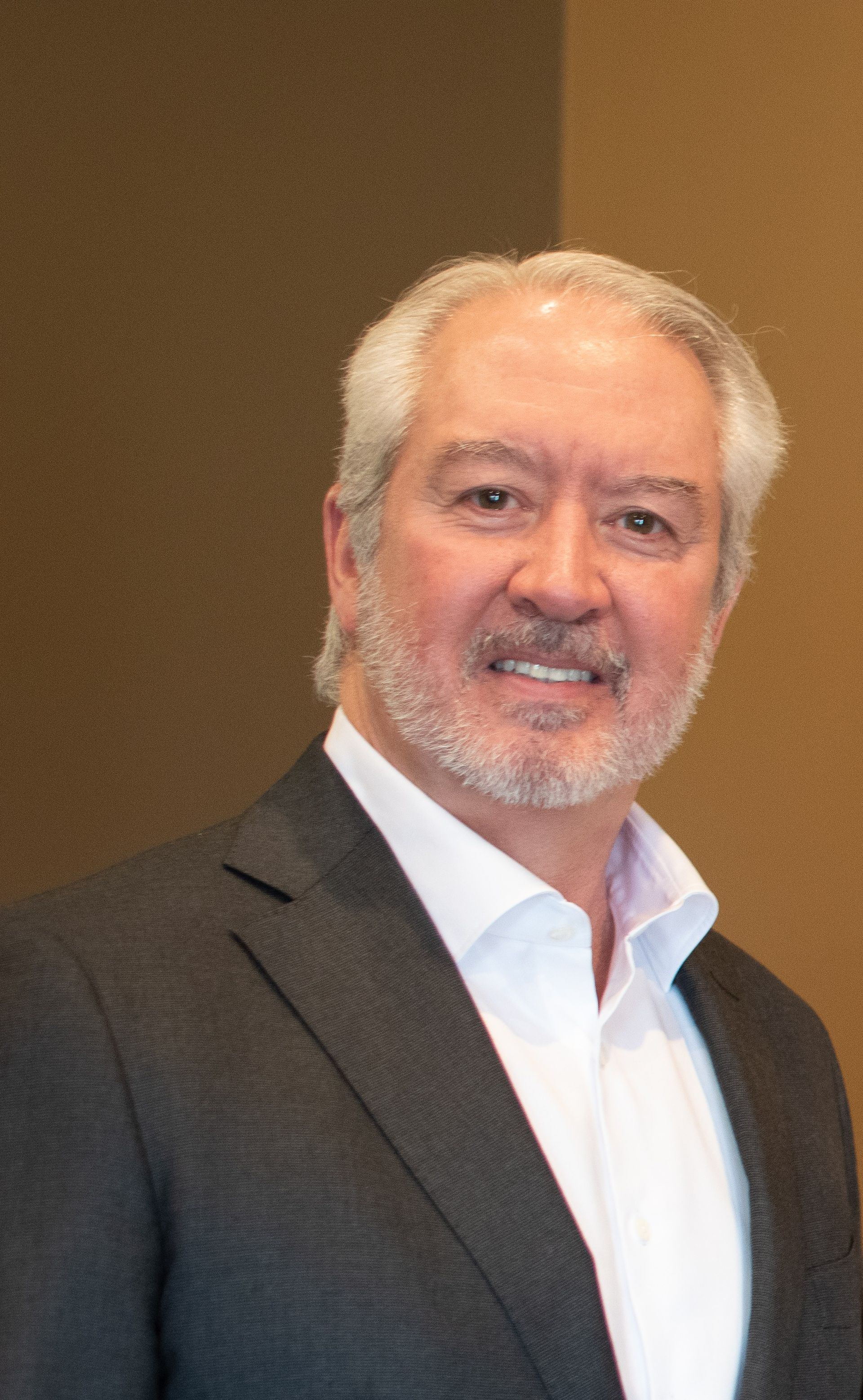A man in a suit and white shirt is smiling for the camera.
