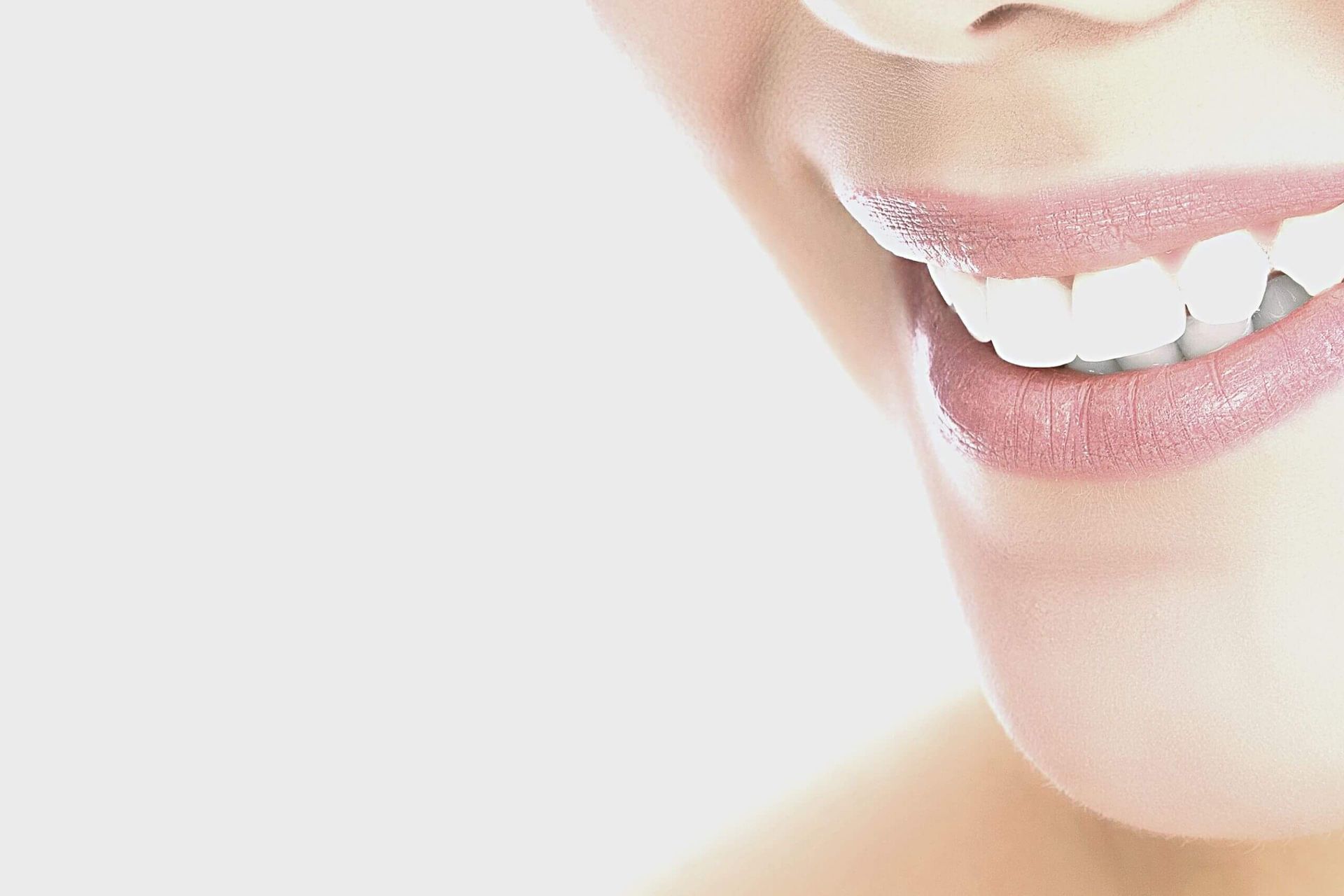 A close up of a woman 's smile with white teeth and pink lips.