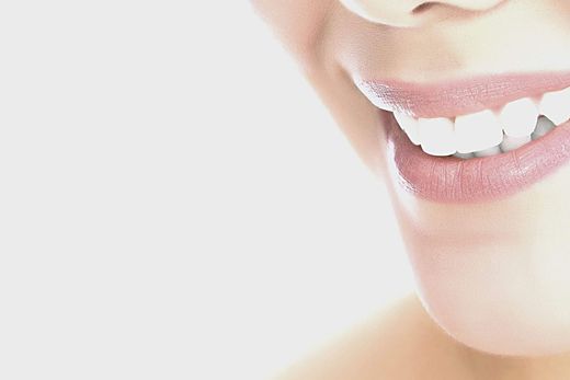 A close up of a woman 's smile with white teeth and pink lips.