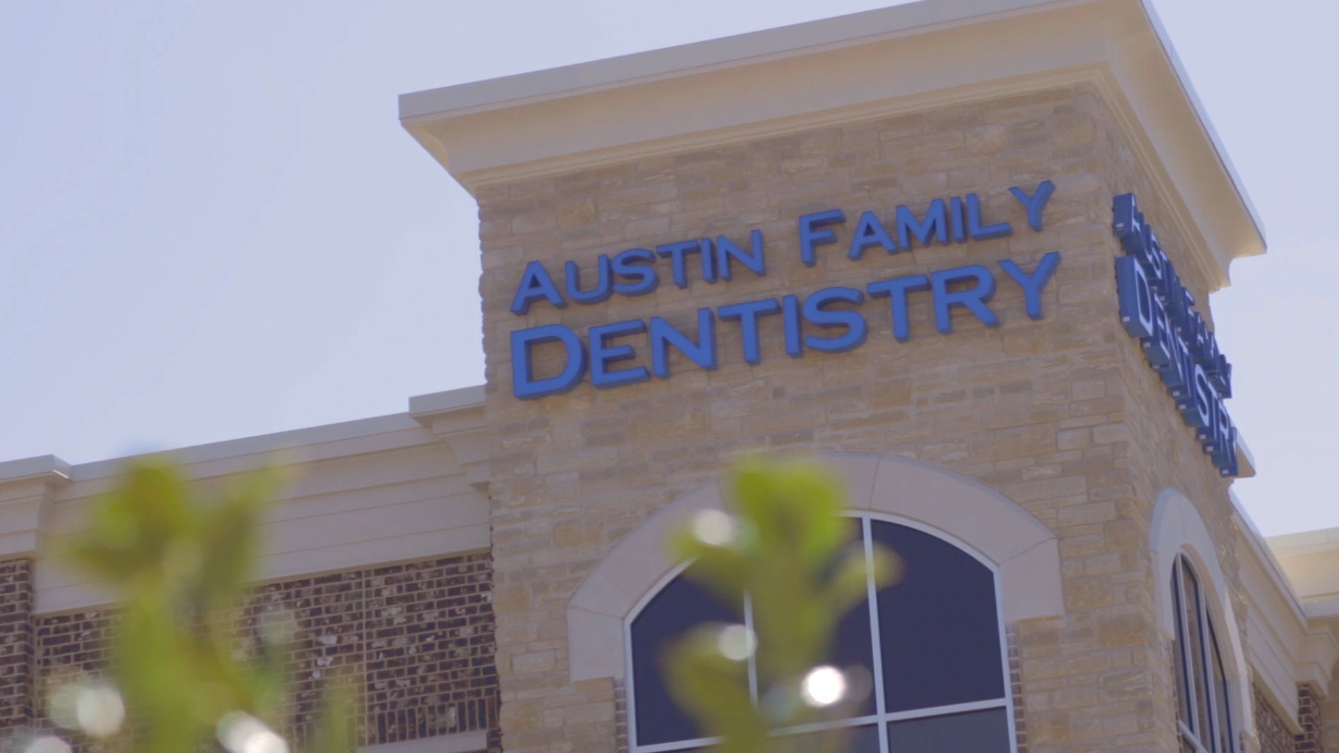 A close up of a dentistry building with a tree in the foreground.
