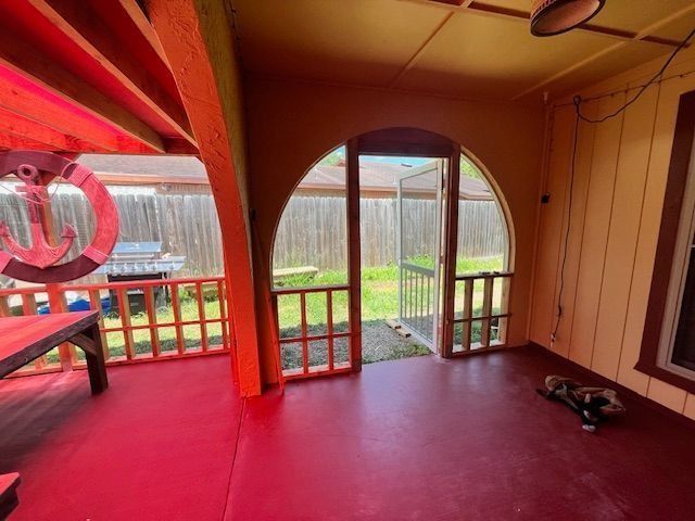 Bright red-painted porch with arched doorway, railing, and outdoor grill