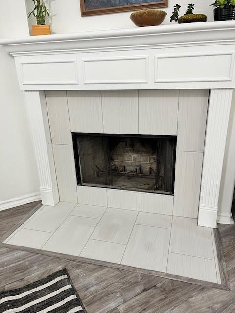 White fireplace with gray tiled surround, black screen, and wooden mantel