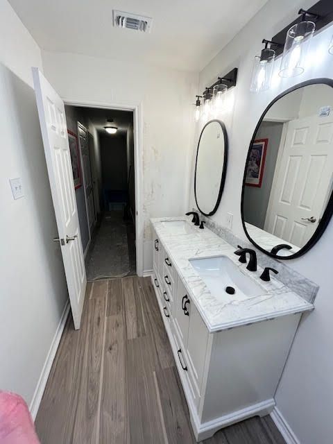 Bathroom with a double vanity, oval mirrors, and light fixtures