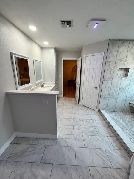 Modern bathroom with gray walls, marble tile floor, double vanity, and large shower