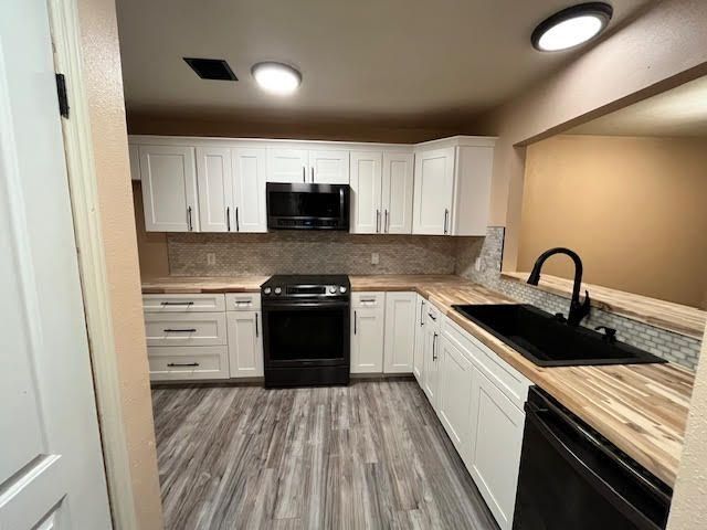 White kitchen with black appliances and a butcher block countertop