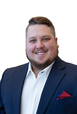Man wearing a blue suit and white shirt, smiling, with a red pocket square.