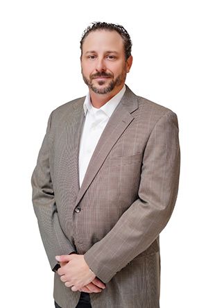 Man in a suit, arms crossed, smiling slightly, standing against a white background.