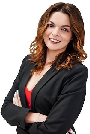 Woman with crossed arms, wearing a black blazer and red top, smiling.
