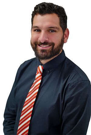 Man with a beard wearing a blue shirt and striped tie, smiling.