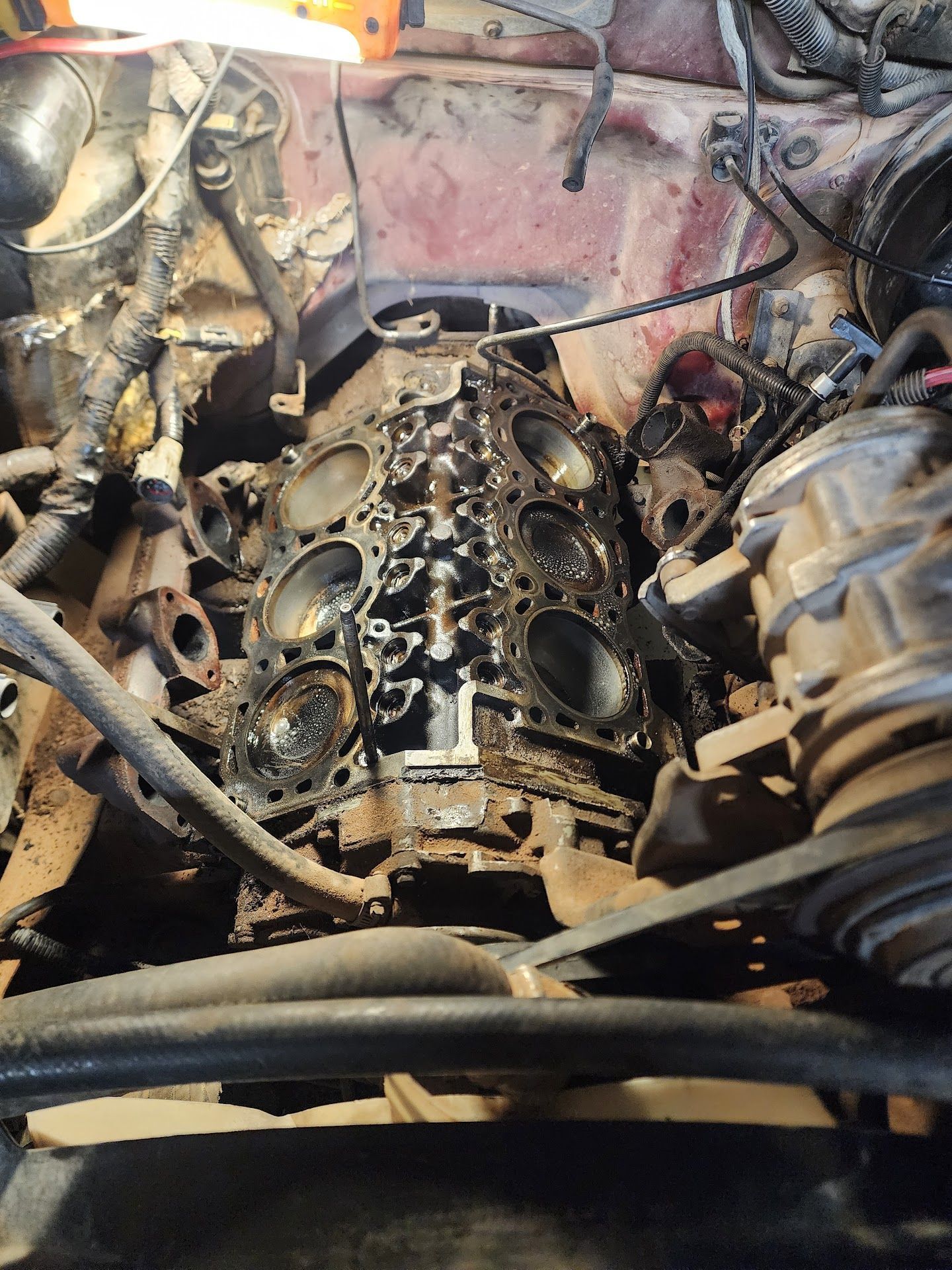 Engine block with exposed cylinders, covered in oil and grime, in a vehicle. | TST Mechanic Services