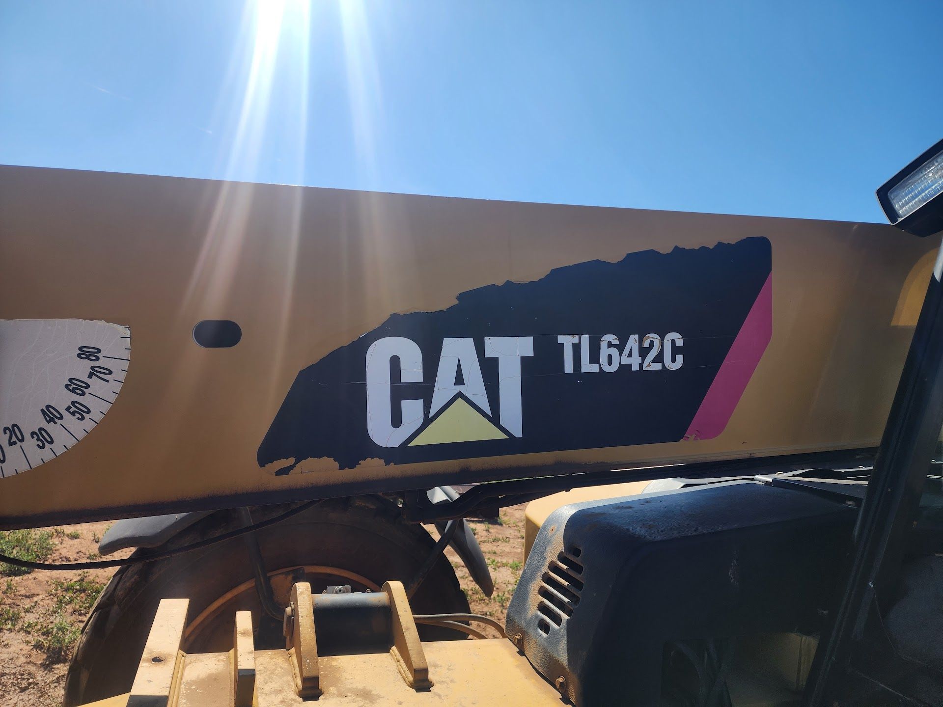 CAT TL642C logo on a yellow piece of construction equipment, against a blue sky. | TST Mechanic Services