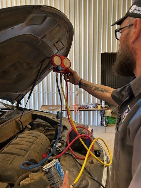 Mechanic using gauges to check car's AC under the hood, outdoors. | TST Mechanic Services