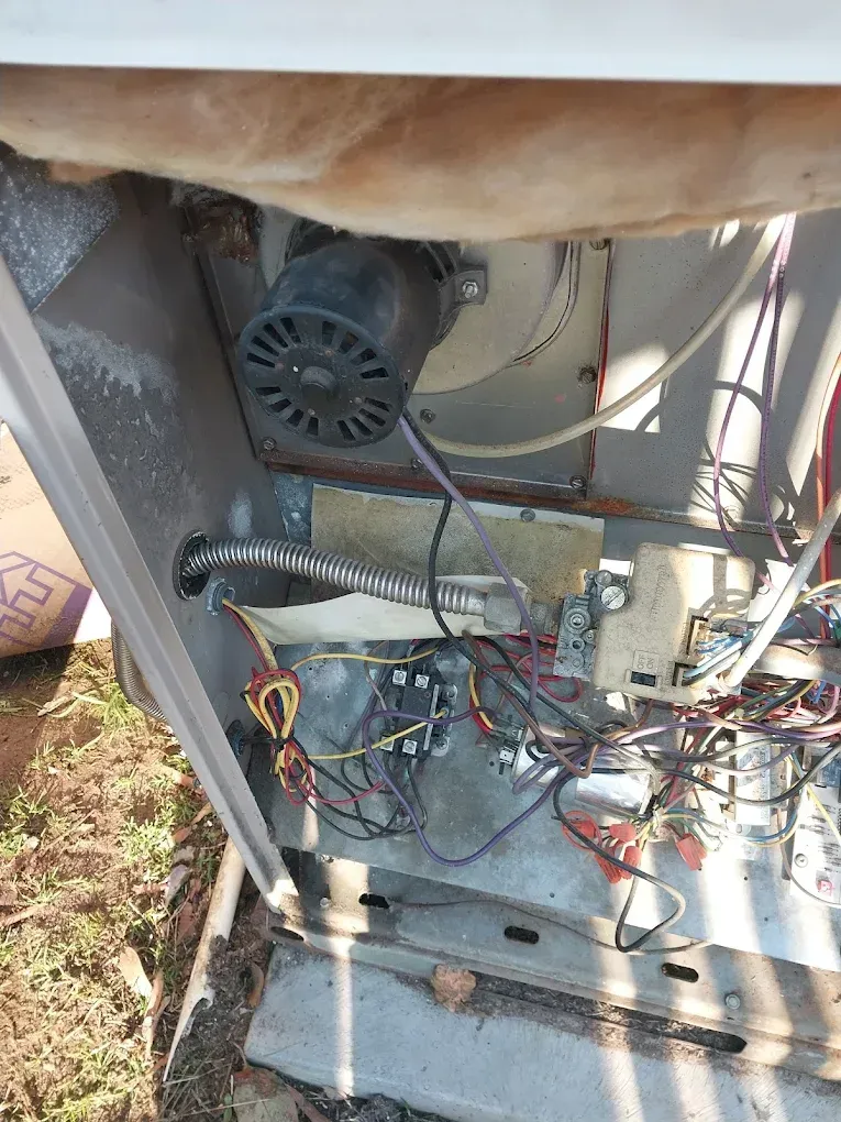 Inside view of an outdoor HVAC unit, showing the blower motor, wiring, and electrical components.