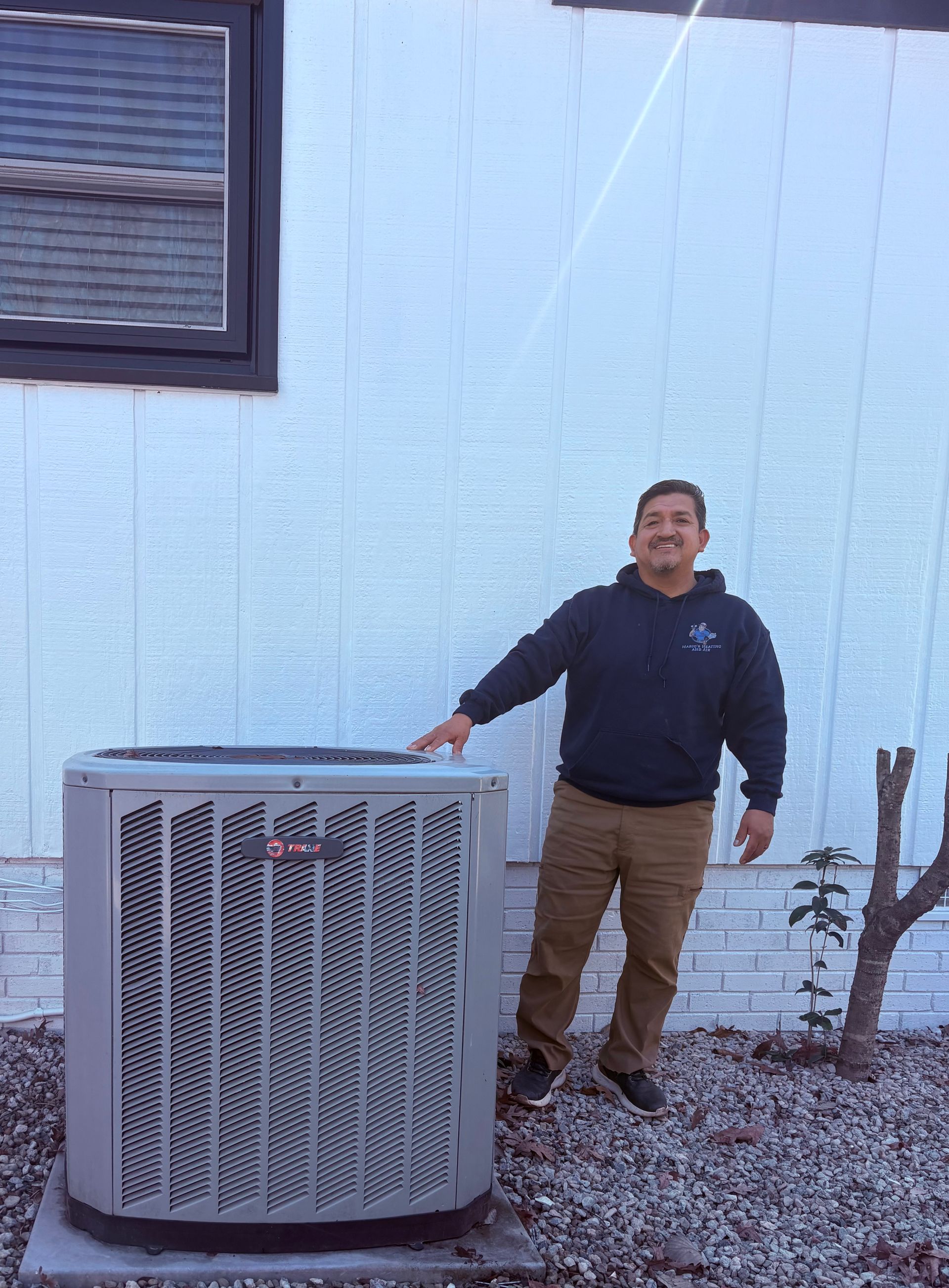 Man points at a large, gray air conditioning unit next to a light blue wall.