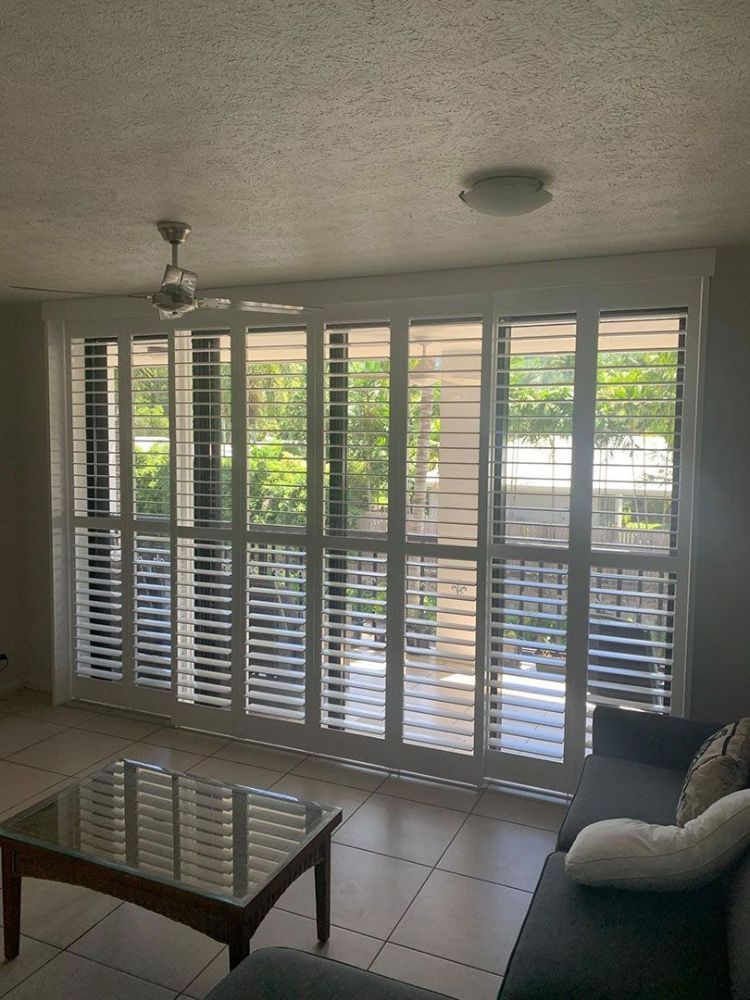 A Living Room with A Couch, Coffee Table, and Shutters on The Windows — Roll Edge In Manunda, QLD