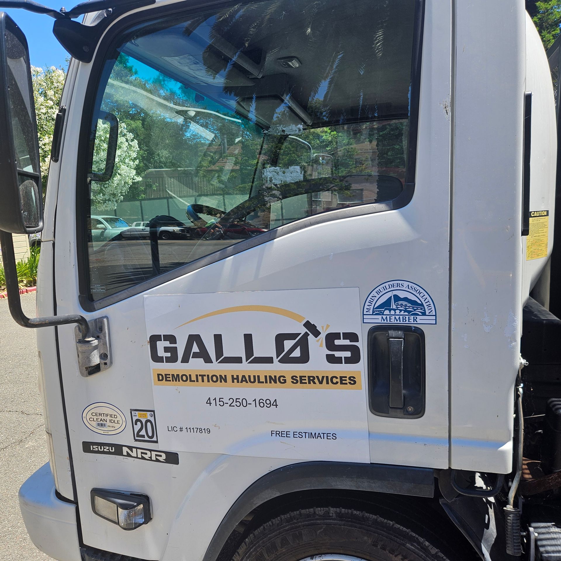 A yellow excavator is loading rocks into a dumpster.