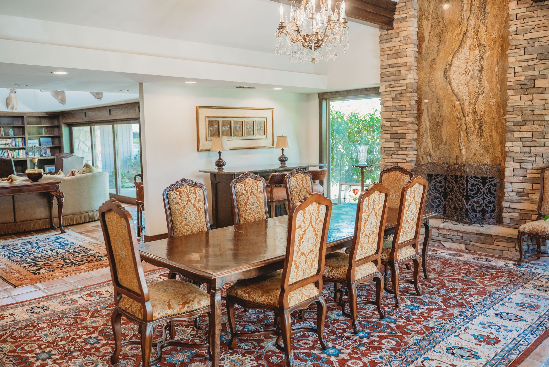 A dining room with a long table and chairs and a fireplace.