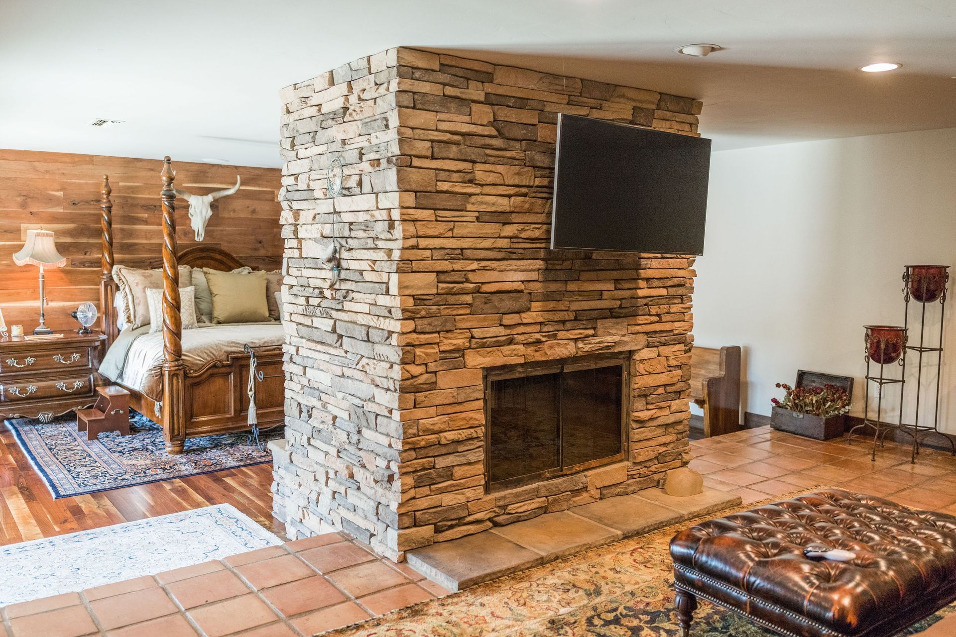 A living room with a stone fireplace and a flat screen tv.