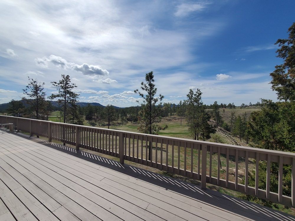 A wooden deck with a railing overlooking a golf course