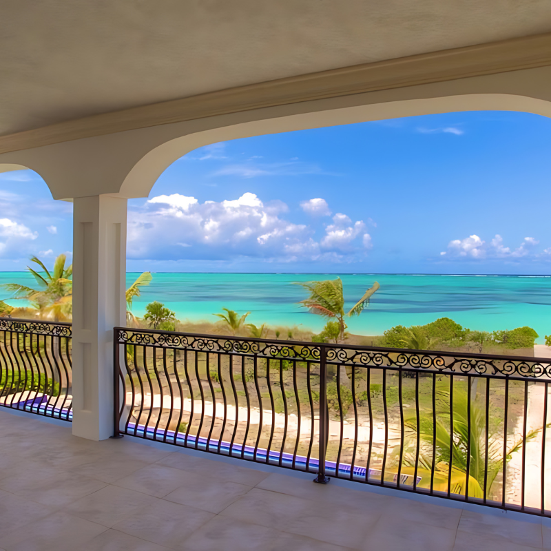 A balcony with a view of the ocean and palm trees