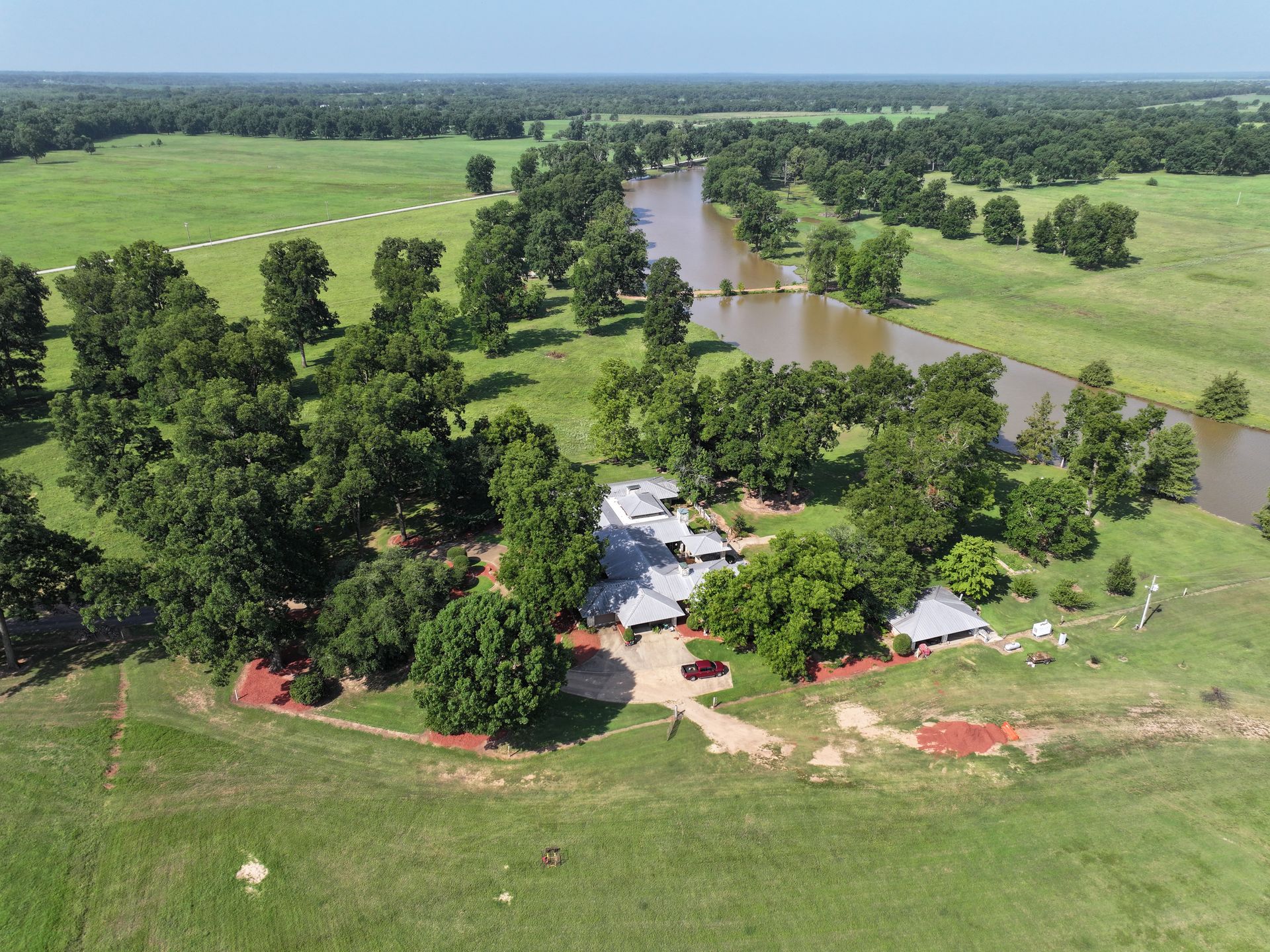 An aerial view of a house surrounded by trees and a river