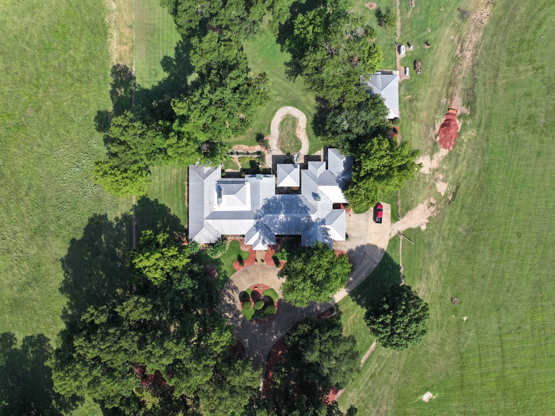 An aerial view of a house surrounded by trees and grass