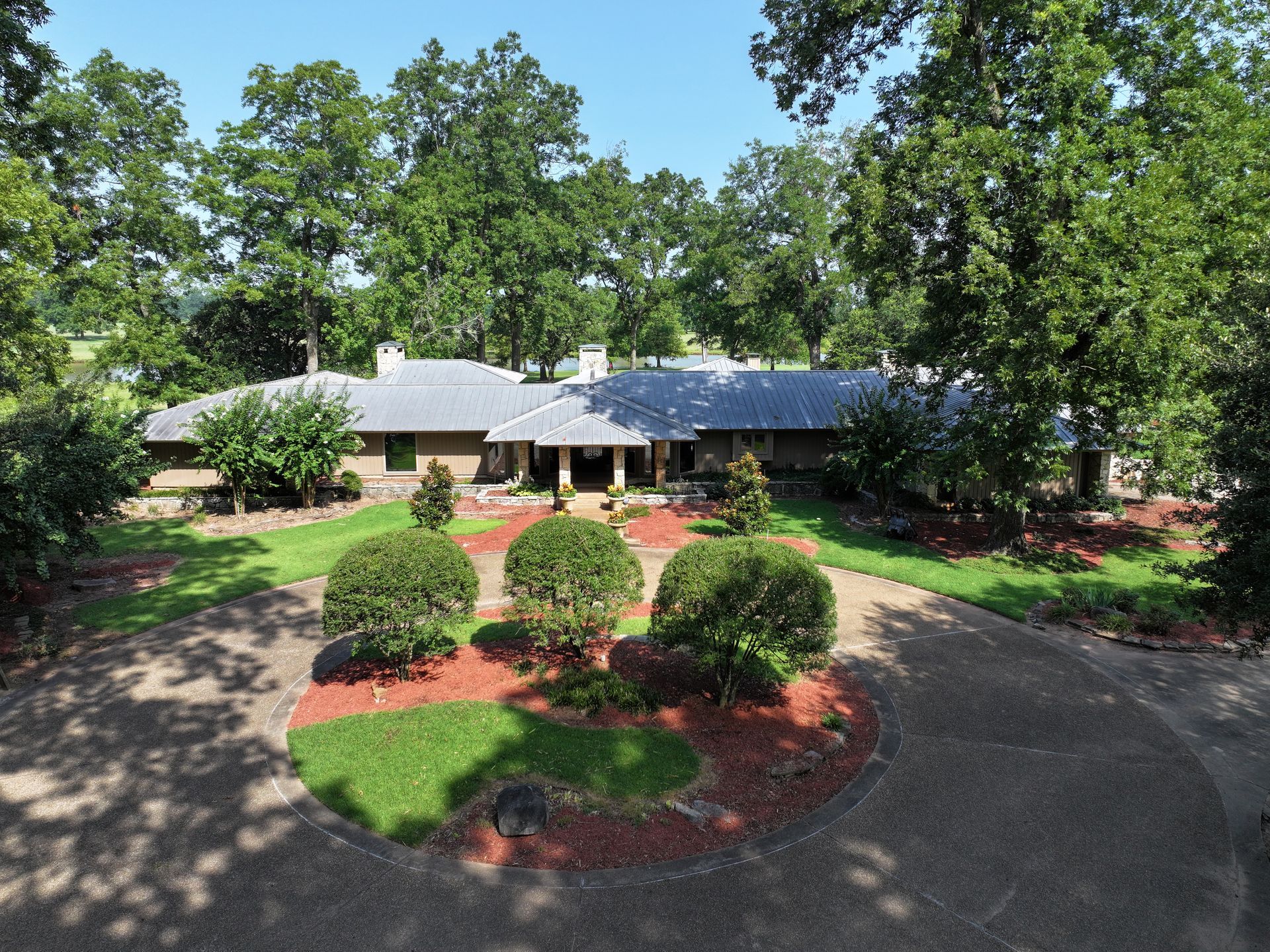 An aerial view of a house surrounded by trees and bushes