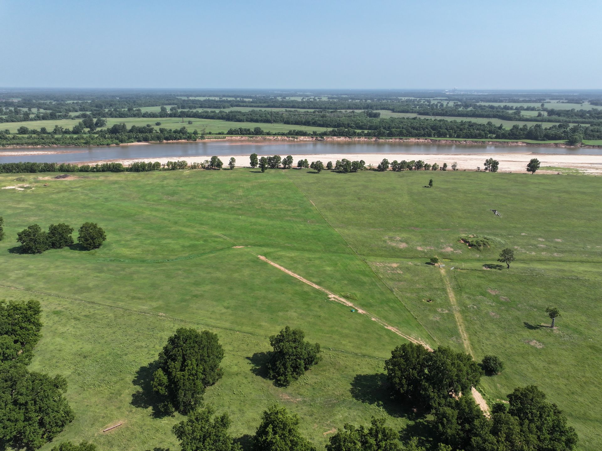 An aerial view of a river surrounded by trees and grass