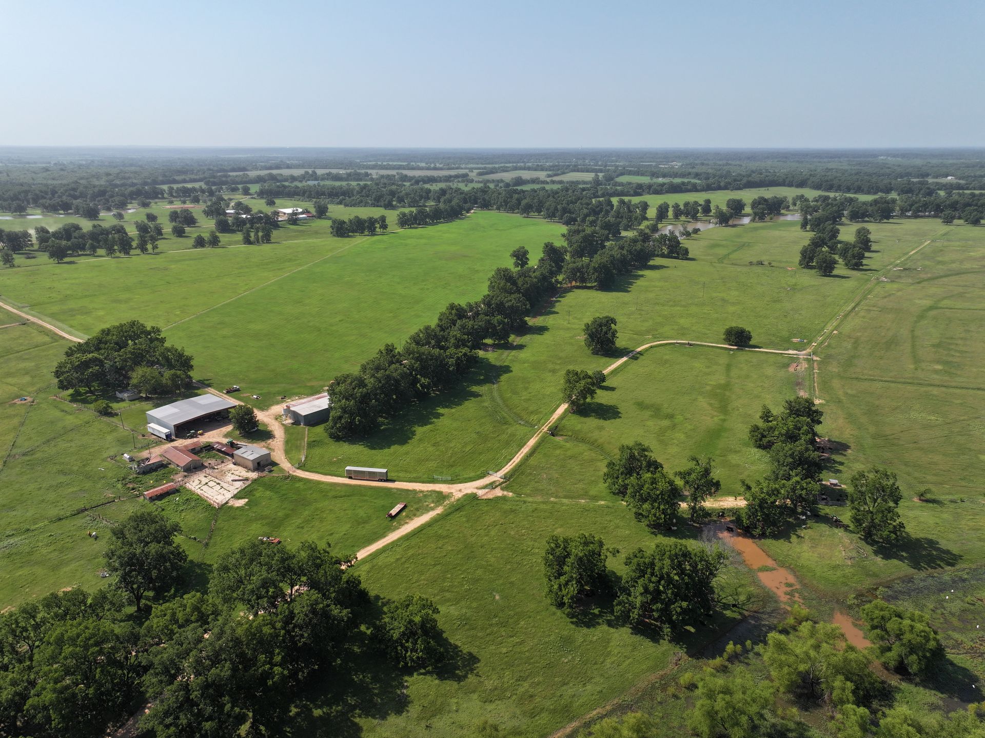 An aerial view of a large grassy field surrounded by trees