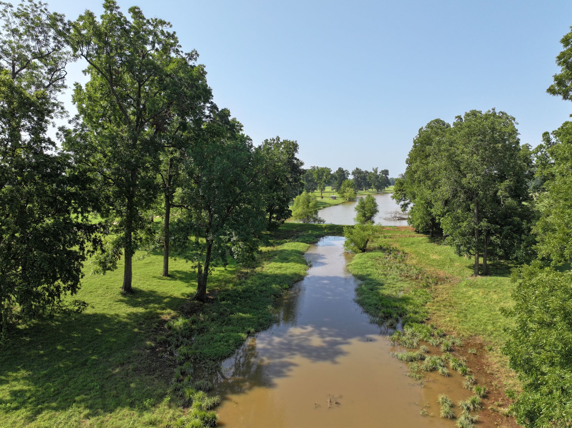 An aerial view of a river surrounded by trees and grass.