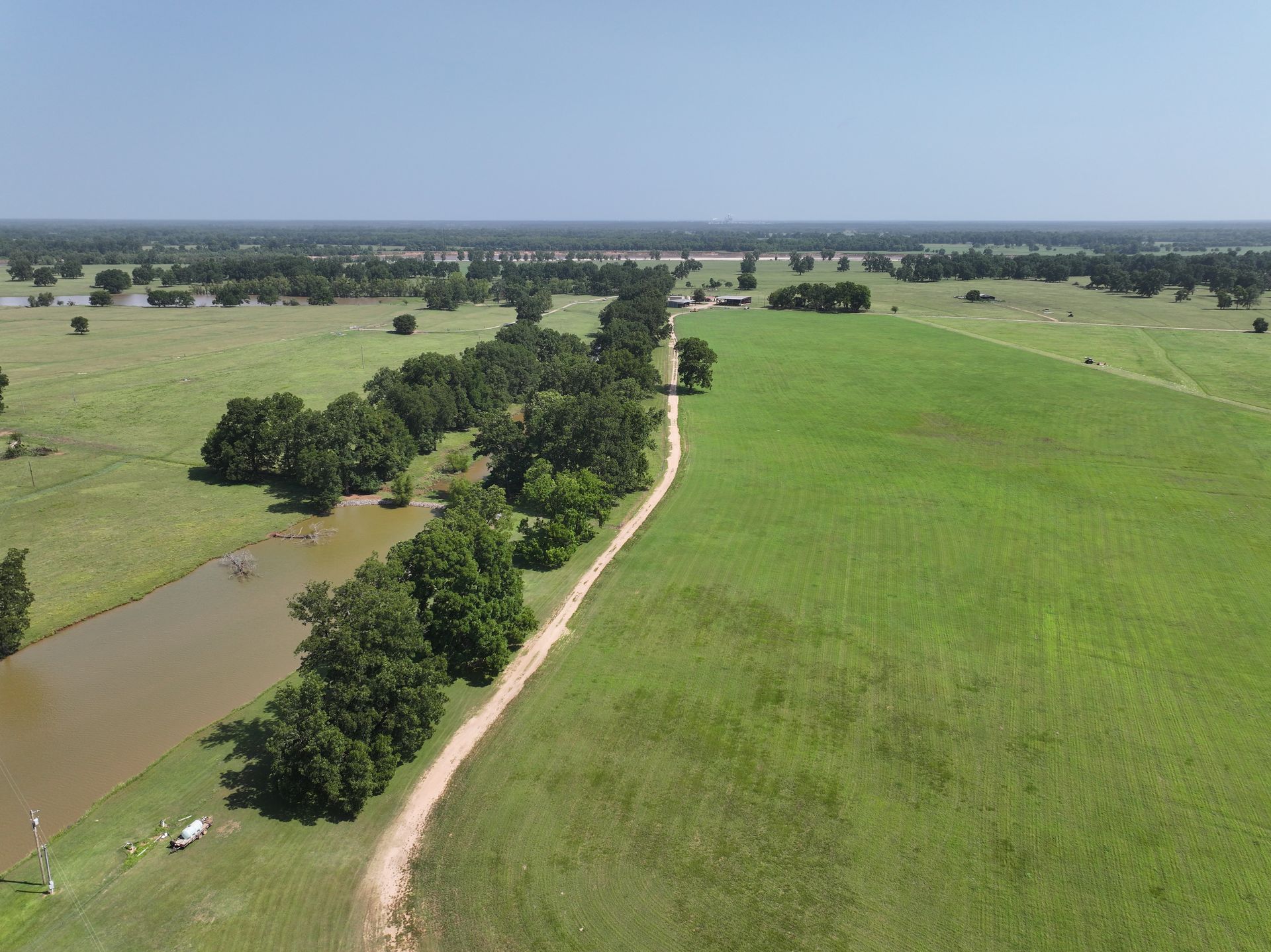 An aerial view of a dirt road going through a grassy field.