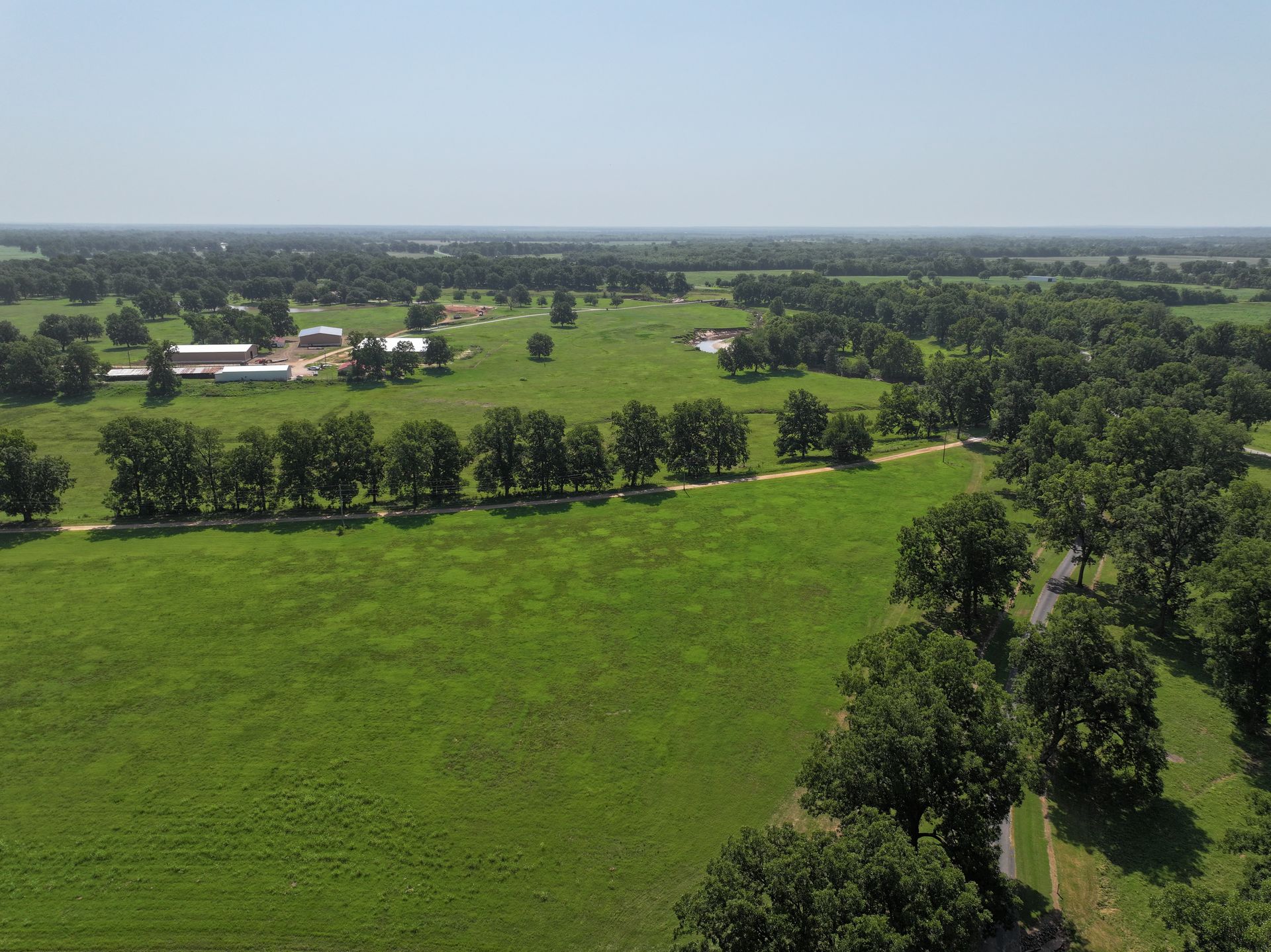 An aerial view of a lush green field surrounded by trees