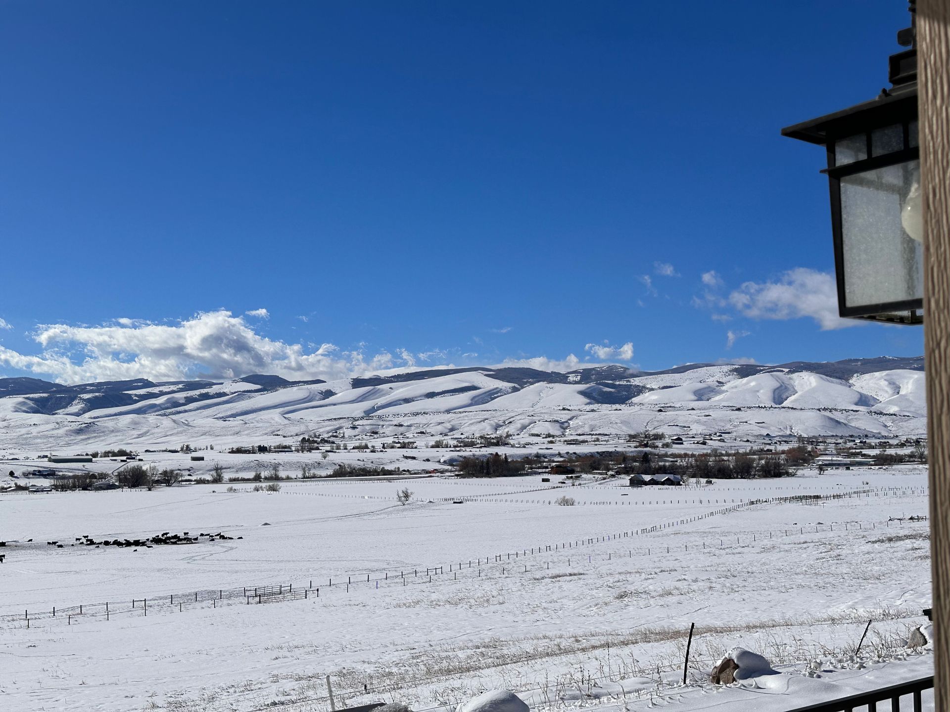 A wide, snowy valley stretches toward rolling, snow-covered mountains under a clear, bright blue sky.