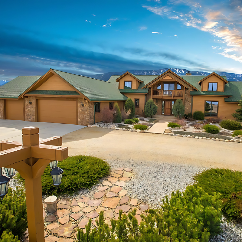 A large house with a green roof and mountains in the background