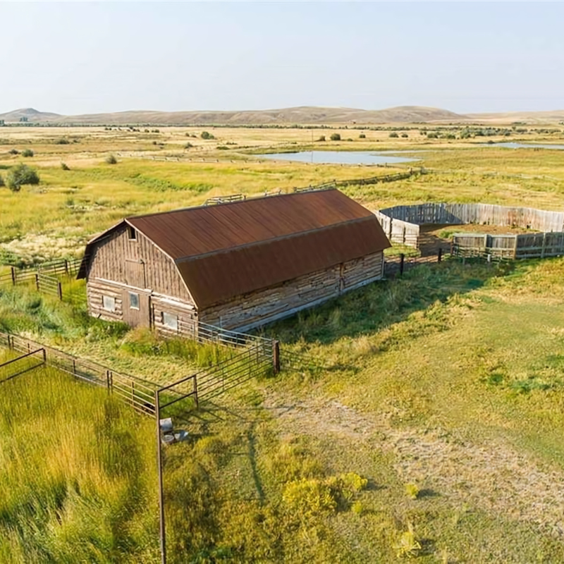 An aerial view of a barn in the middle of a grassy field.