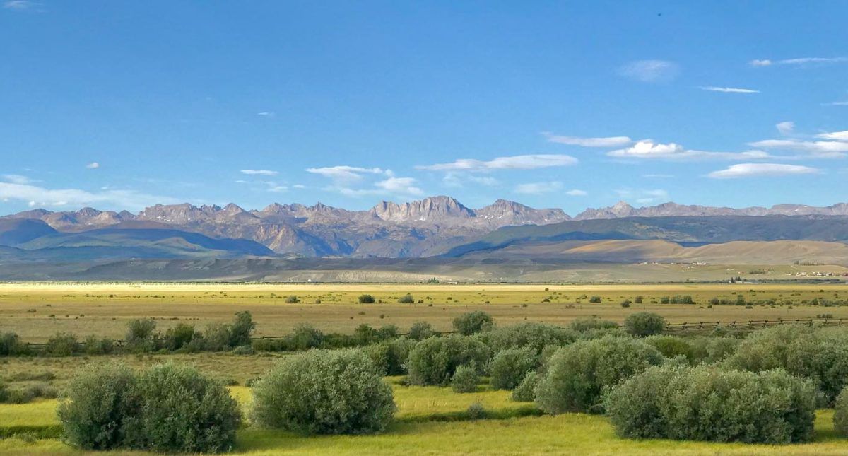 An aerial view of a rural property featuring a white barn, several trailers, outbuildings, and a dirt riding arena.