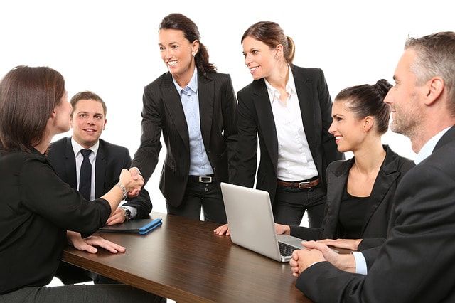 Picture of a group of Business people shaking hands around a computer.