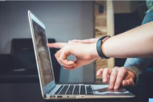 Picture of hands pointing at a laptop screen.