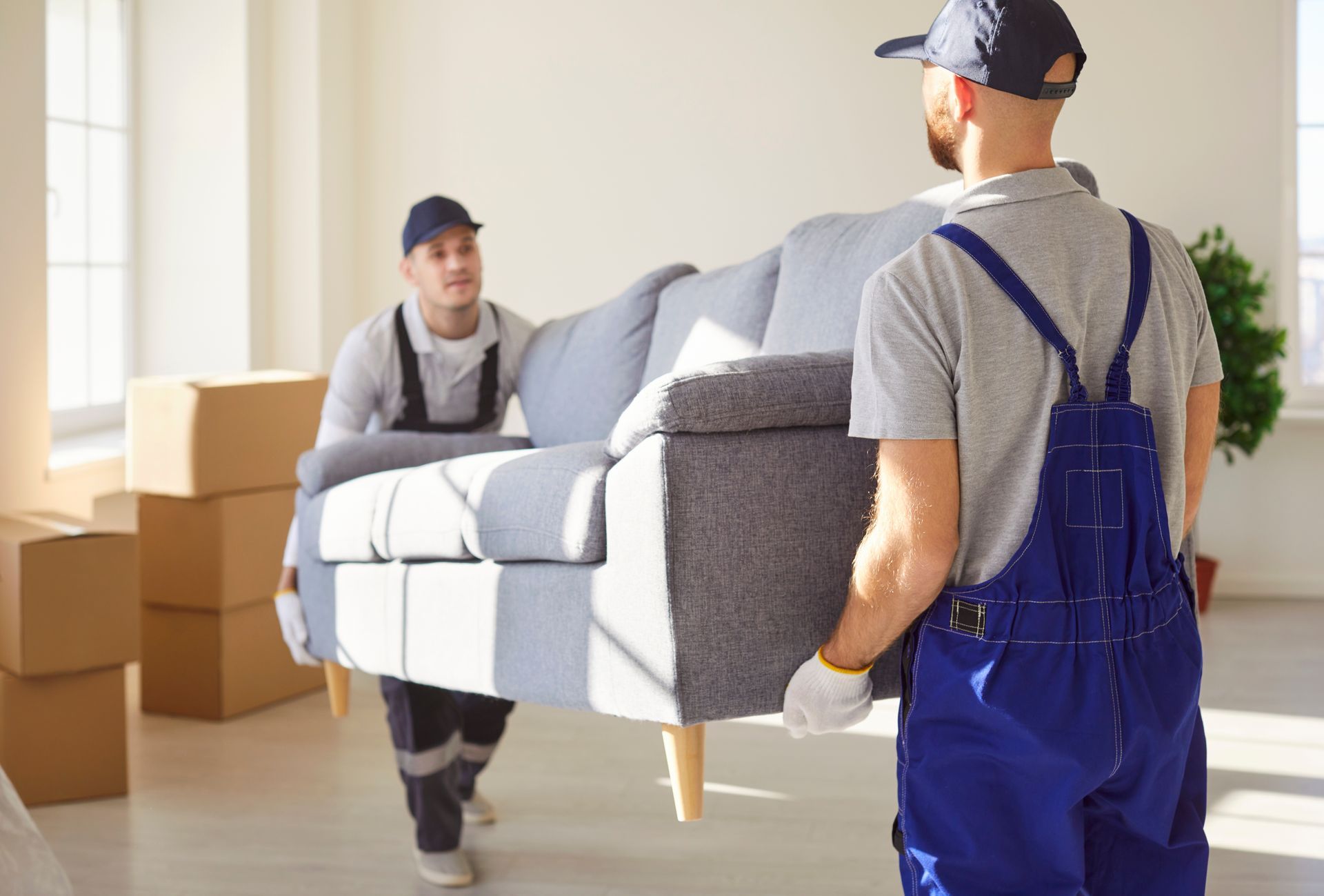 Two men in overalls transporting a couch, highlighting the efforts of local movers during a move.