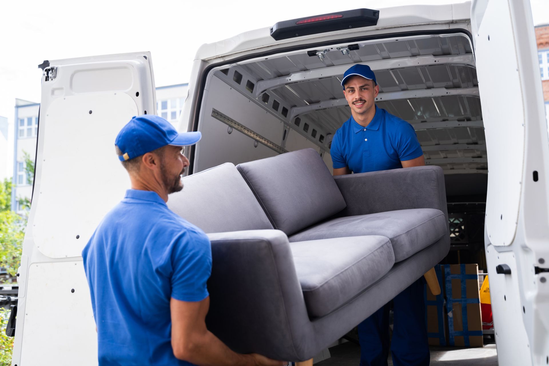 Two Moving Workers carrying a sofa to a moving truck