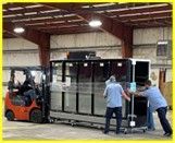 A forklift is moving a large piece of glass in a warehouse.