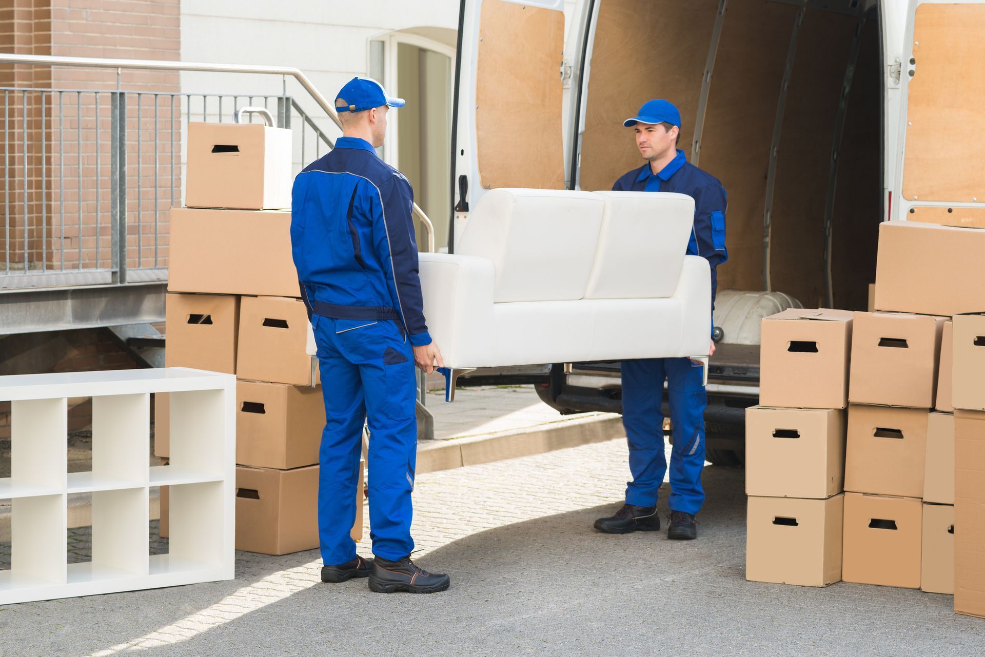 Two men in uniform working for a moving company carrying a sofa